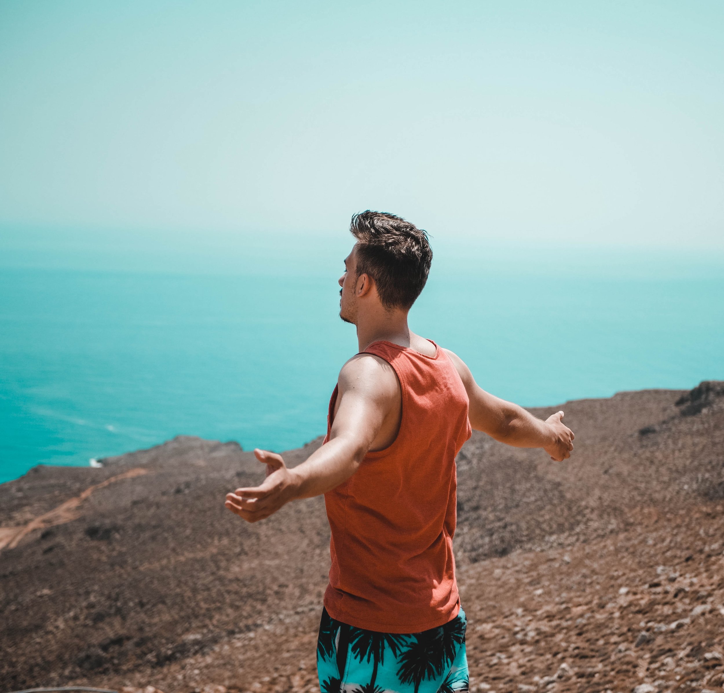 man standing on mountain with arms outstretched