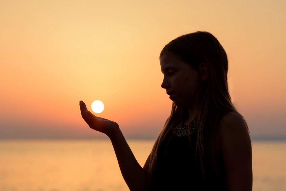 girl holding sun in her hand