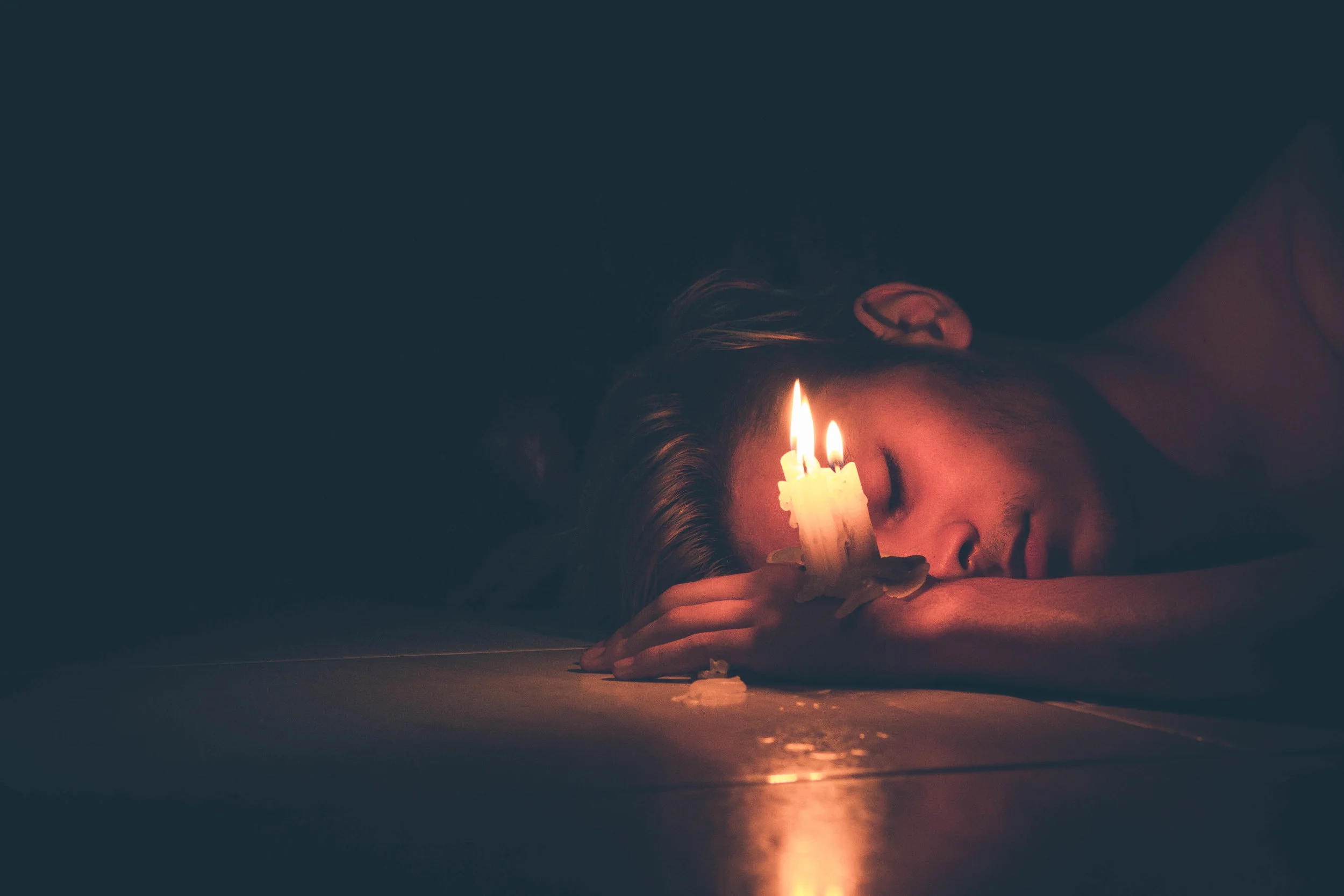 depressed man laying on ground with candle