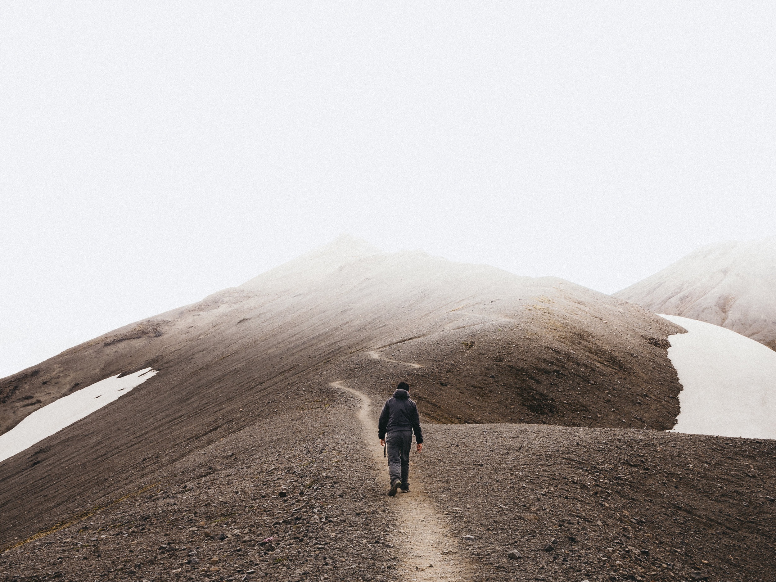 man walking alone on mountain trail