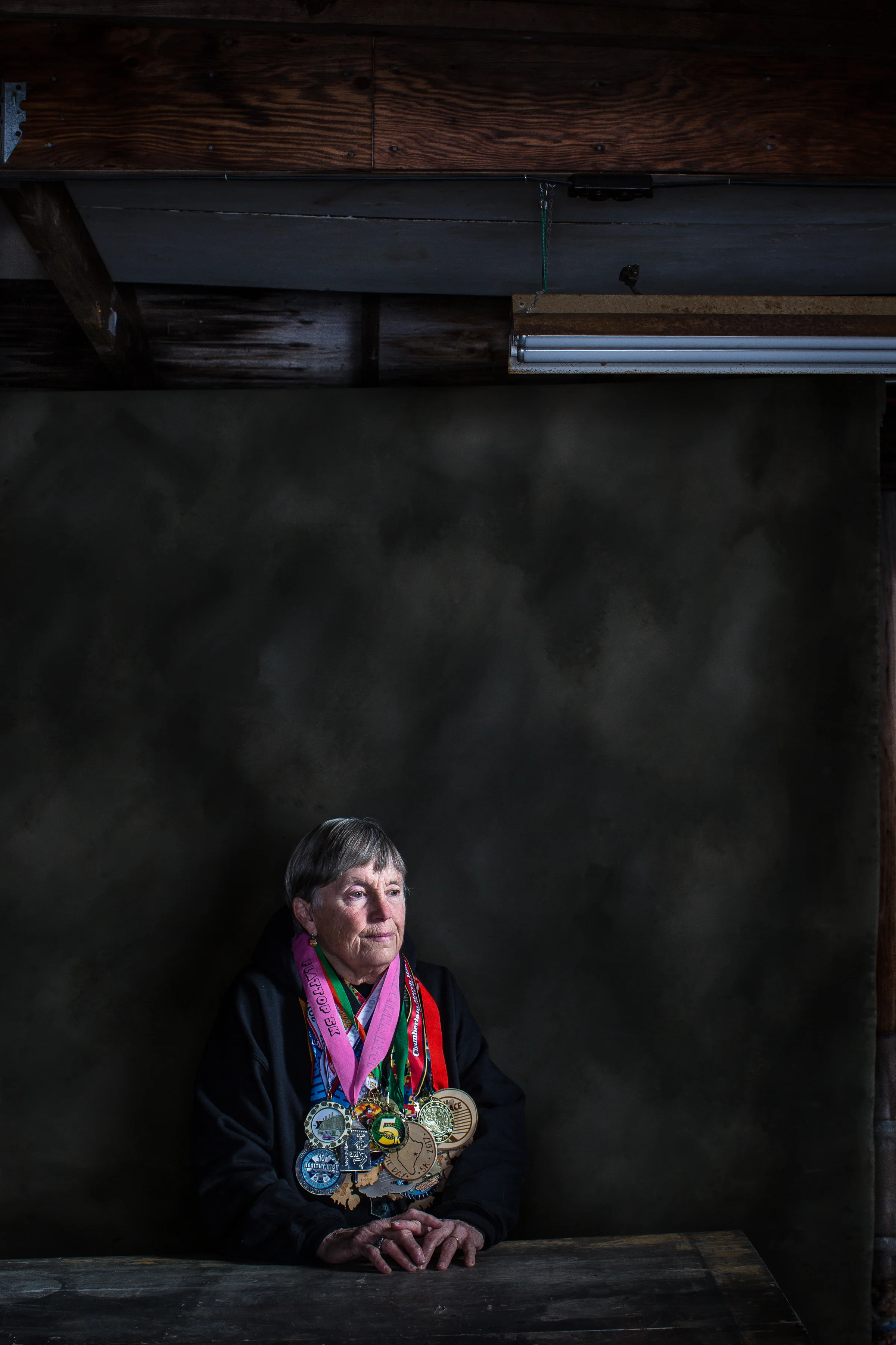 Robin Emery, 72, of Lamoine, Maine has been running races for more than 50 years and logged enough miles to circumnavigate the globe one and a half times. Participating in approximately 30 races a year and running every day, she has pushed through physical adversity, such as once suffering a frozen eyeball due to weather conditions (she now runs with ski goggles in colder temps), and also broken through societal norms. When Robin signed up to run her first race in 1972, she was the first woman to ever enter the race. “Women weren’t supposed to sweat or be competitive then,” she said. “It wasn’t feminine.” After entering the race and completing it three years in a row, she was finally given recognition: a basketball trophy, with a man on top. Photographed here in the garage of her family’s home since the early 1900s, Robin’s house is now filled with a life story of trophies, medals, race photos, plaques and memories from the myriad races she’s won and participated in over the decades. Robin, who also was an elementary school teacher for more than 50 years, has a long-standing legacy in Maine. She was the second woman to ever be inducted into the Maine Running Hall of Fame, and also has a trophy named after her at that same Labor Day race.