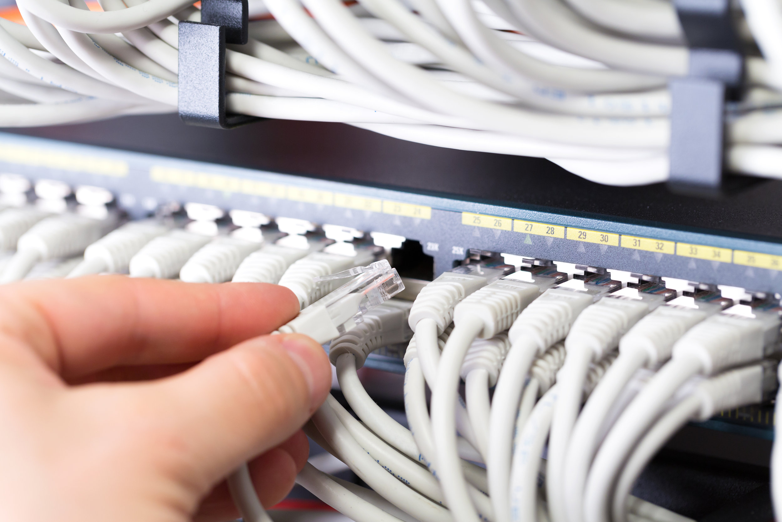 IT consultant connects a network cable into switch in datacenter