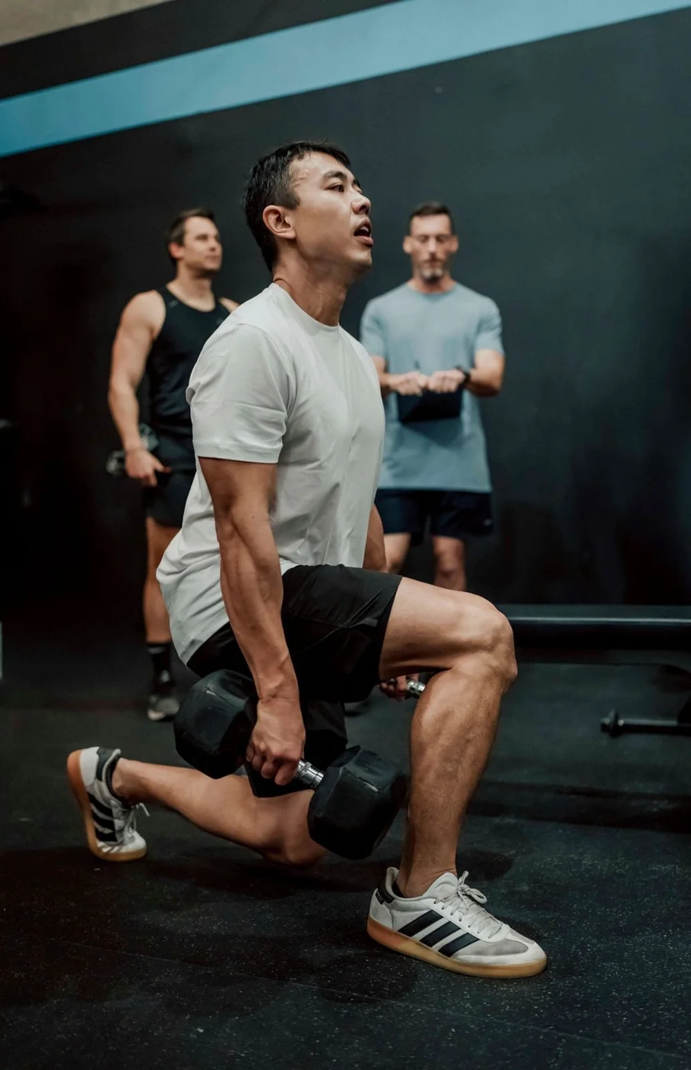 Member doing a dumbbell lunge with coaches watching at Accelerate Strength, Balmain