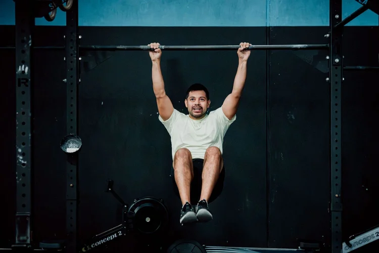 New member hanging from a rig with knees raised during the CrossFit 10-Day Experience at Accelerate Strength