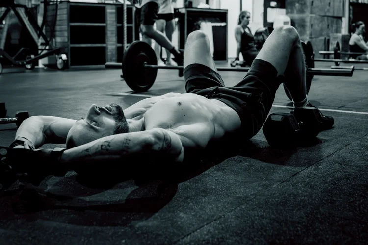 Athlete resting on the gym floor beside a loaded barbell after a personal training session in Balmain