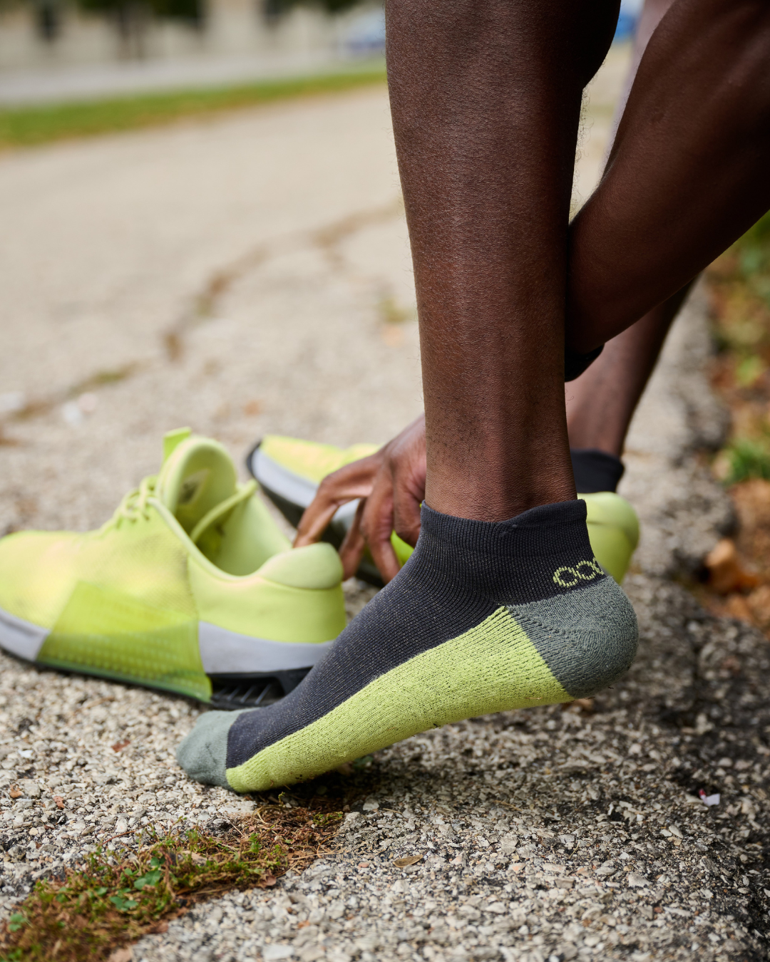Person wearing Agogo Active performance ankle socks in gray and neon green while preparing for a workout, breathable cushioned design for active comfort.