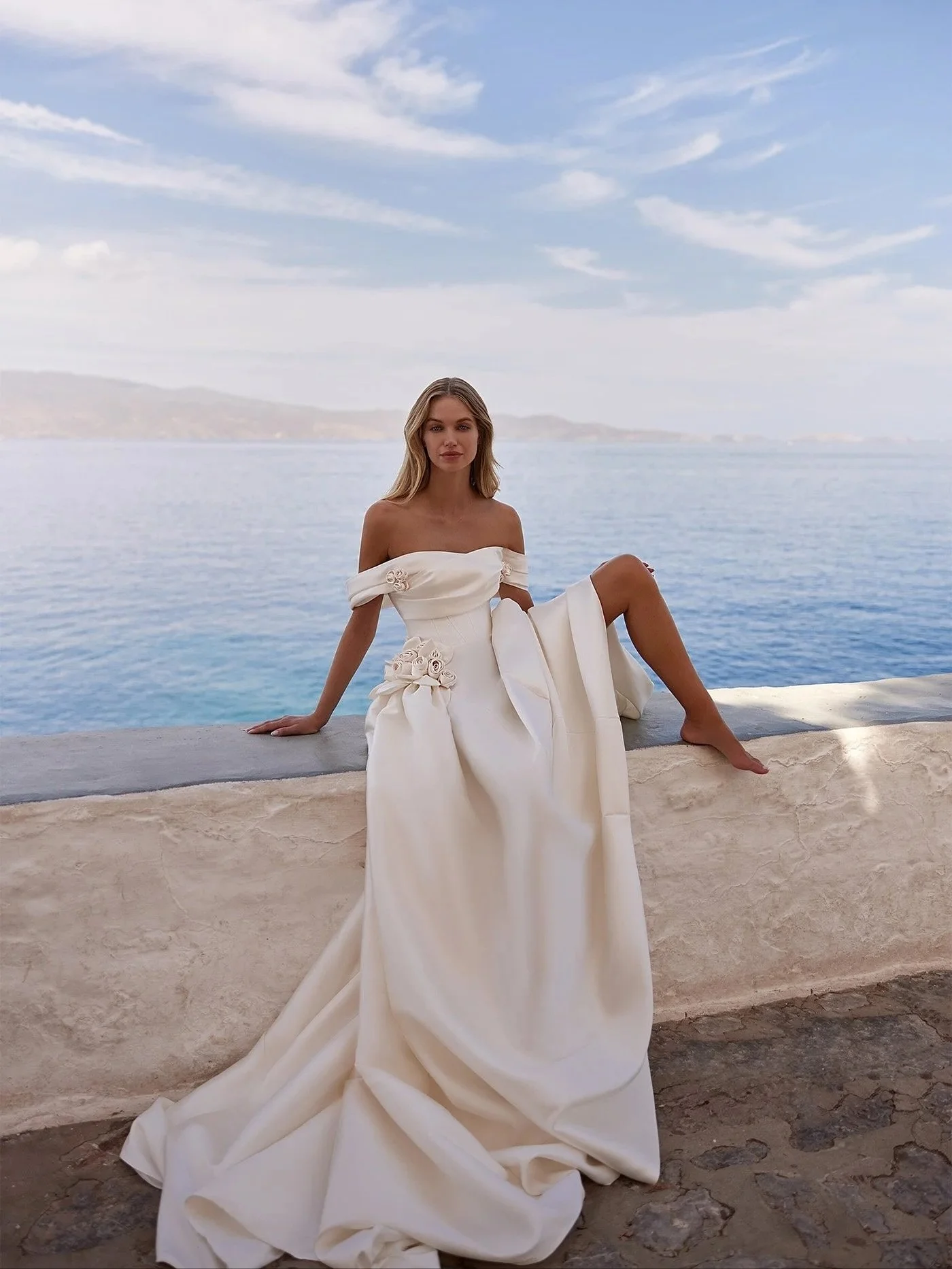This off-the-shoulder ballgown stuns in luxurious mikado, featuring a structured corset bodice and artfully placed 3D floral details at the waist. A statement silhouette designed for the bride who dreams of unforgettable elegance.

#bgsbride #bridal 