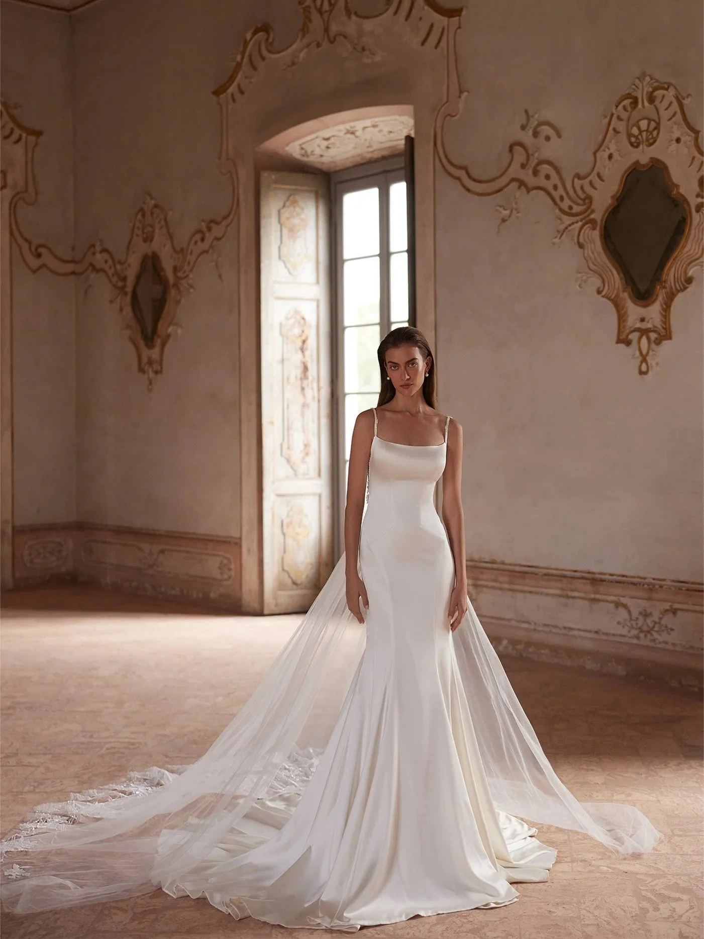 Clean lines in the front, couture artistry in the back. This gown blends sleek satin with a barely-there lace illusion for a look that&rsquo;s timeless, effortless, and unforgettable.