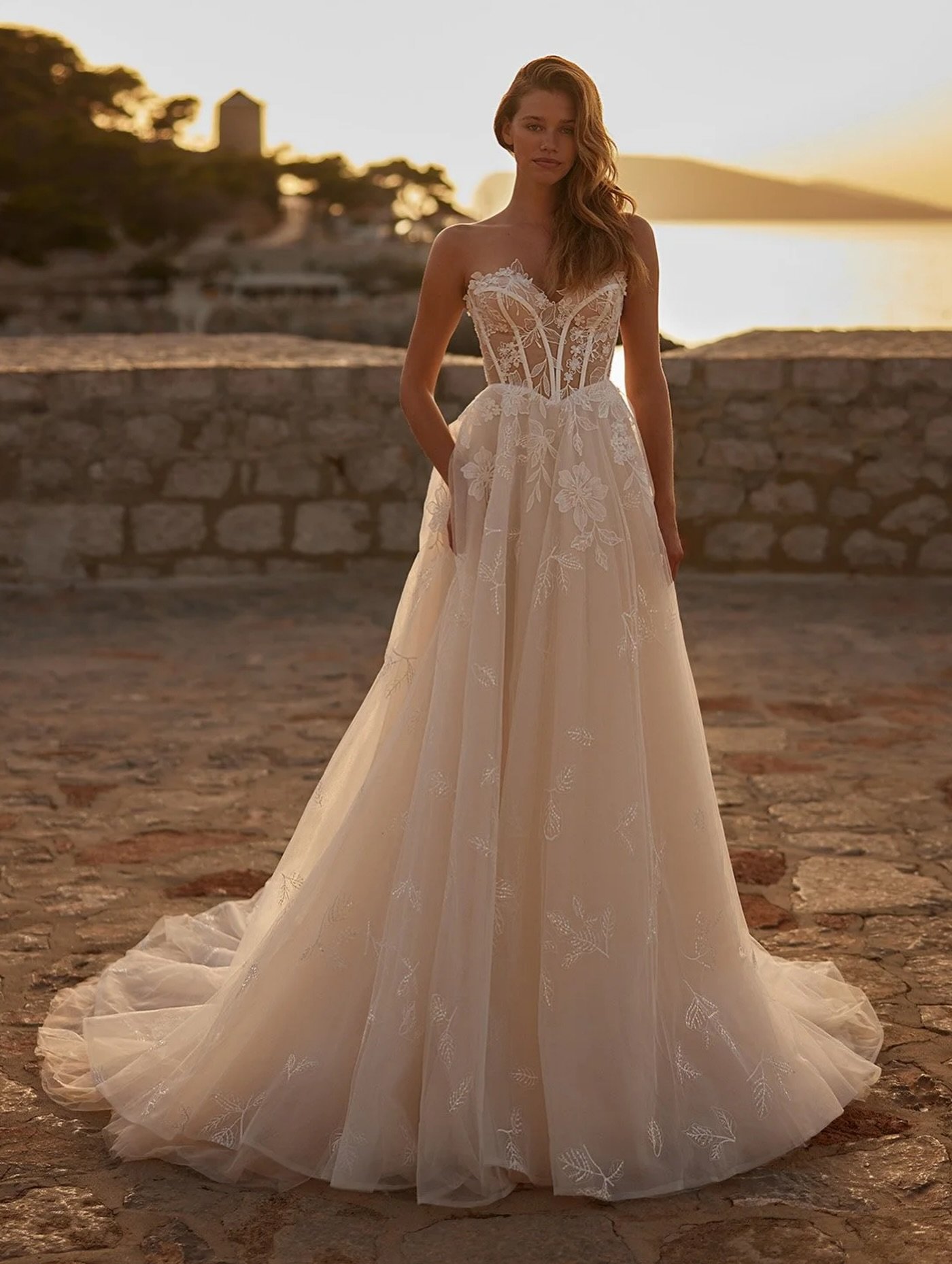 Golden hour perfection. ✨
This strapless A-line gown features a sheer lace corset with sculpted boning, delicate floral embroidery, and a soft tulle skirt that floats with every step. Romantic, effortless, and made for sunset vows and timeless love s