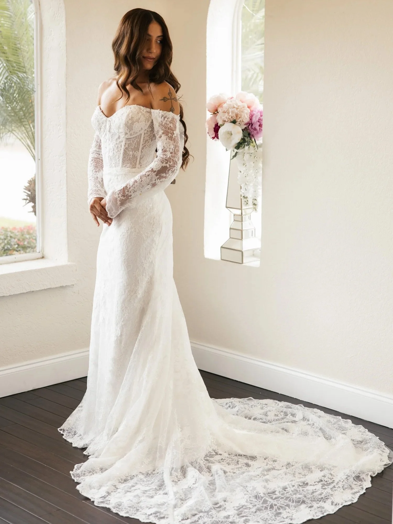 For the romantic bride who loves lace but wants it to feel modern. Sheer sleeves, a contoured fit, and a train that feels undeniably bridal.

romantic lace wedding dress, modern bridal gown, sheer sleeve wedding dress, fitted lace silhouette, off-the