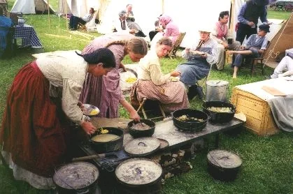 Made July 1997 at Fort Bridger Wyoming. Re-enactors in the "Authentic Camp." Photograph by Steve Berlin. The "Authentic Camp" docents from Old Deseret Village at The Place State Park in Salt Lake City, Utah. They are shown having a pioneer supper. This living history group was with the company throughout the trek and adhered as closely as possible to the means and methods of pioneer times.
