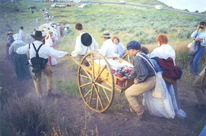 Made July 20, 1997 on a hill just north of East Canyon reservoir, East Canyon, Utah. This scene depicts, Handcart Struggles. Photograph by Steve Berlin. This handcart was made in Russia, pulled across Siberia and Ukraine and flown from Moscow to Salt Lake City for the final leg of the trek. It bears gifts made by members of the LDS Church in several Slavic countries for the church president. East Canyon Reservoir is seen in the upper right.