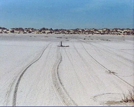 10. Made 9/23/87 Great Salt Desert, Utah. Approaching the Dunes on the East Side. Photograph: Copyright © 1987 Roy D. Tea. The east side of the Great Salt Lake Desert is marked by sand dunes as well as stretches of flats. Softer ground to the north in this area prevented the emigrants from taking a direct route toward Pilot Peak, at the foot of which, they knew they would find water. Here the trail approaches an area of dunes after passing through a small depression. To climb up on the dunes, the trail curves to the right but then straightens and proceeds nearly due west again. A 6" aluminum pipe can be seen near the center of the photograph which has just been placed to mark the trail by Dan Miller Jr. and Roy Tea.
