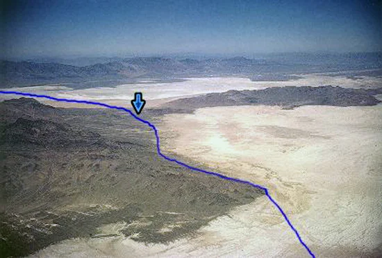 27. Made Summer, 1963, Great Salt Lake Desert, Utah. Donner-Reed Pass, Silver Island - Crater Island, UT. Photograph: Copyright © 1963 Roy D. Tea. View northwest. The blue line approximates the trail which runs from bottom to top. Having proceeded mostly northwest across the flat the trail turns a little to the west at Silver Island Point, lower right. The arrow marks Donner-Reed Pass where the trail crosses the narrow neck of land connecting Silver Island, left, and Crater Island, right. Beyond the pass the trail crosses the final eight miles of flat bearing slightly north of due west before reaching Donner Spring, at the foot of Pilot Peak, out of the picture on the left.