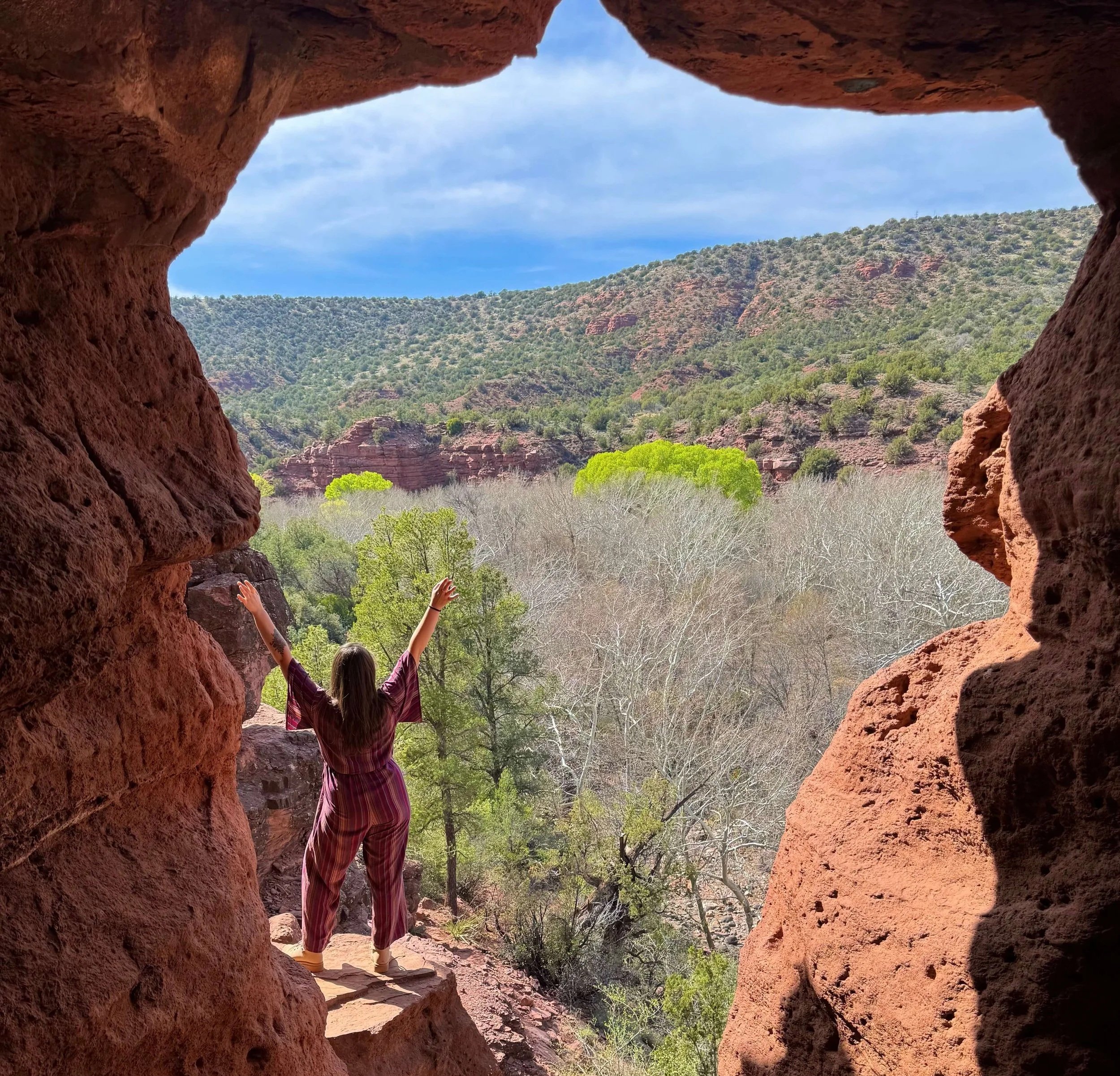 Woman discovering a red rock cave along hikes around Sedona, showcasing the area as a featured outdoor attraction