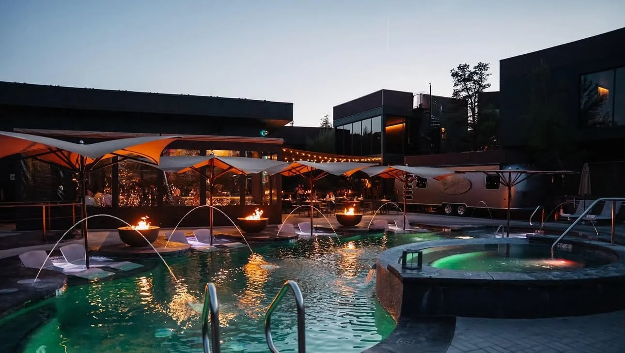 Ambiente a landscape hotel at sunset with a glowing pool and fire pits creating a warm, inviting atmosphere