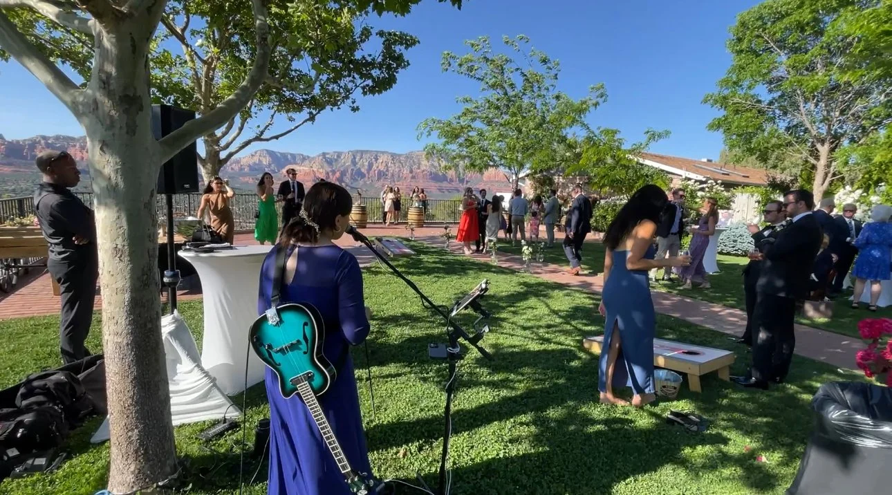 Sedona wedding location with a multi-instrumentalist performing at an outdoor cocktail hour as guests mingle and enjoy sweeping red rock views