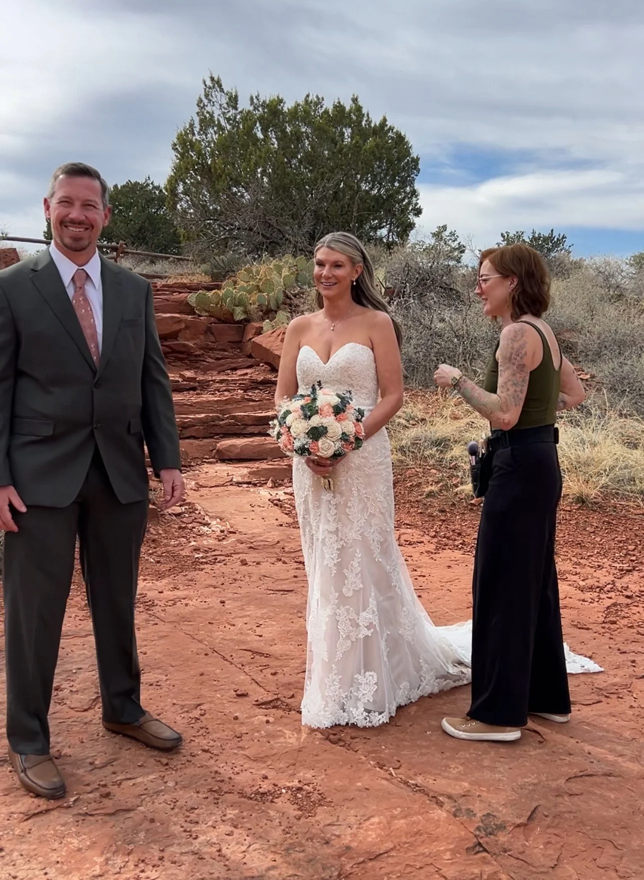 Wedding hair and makeup artist performing final touchups on the bride’s hair before family photos with Sedona red rocks in the background