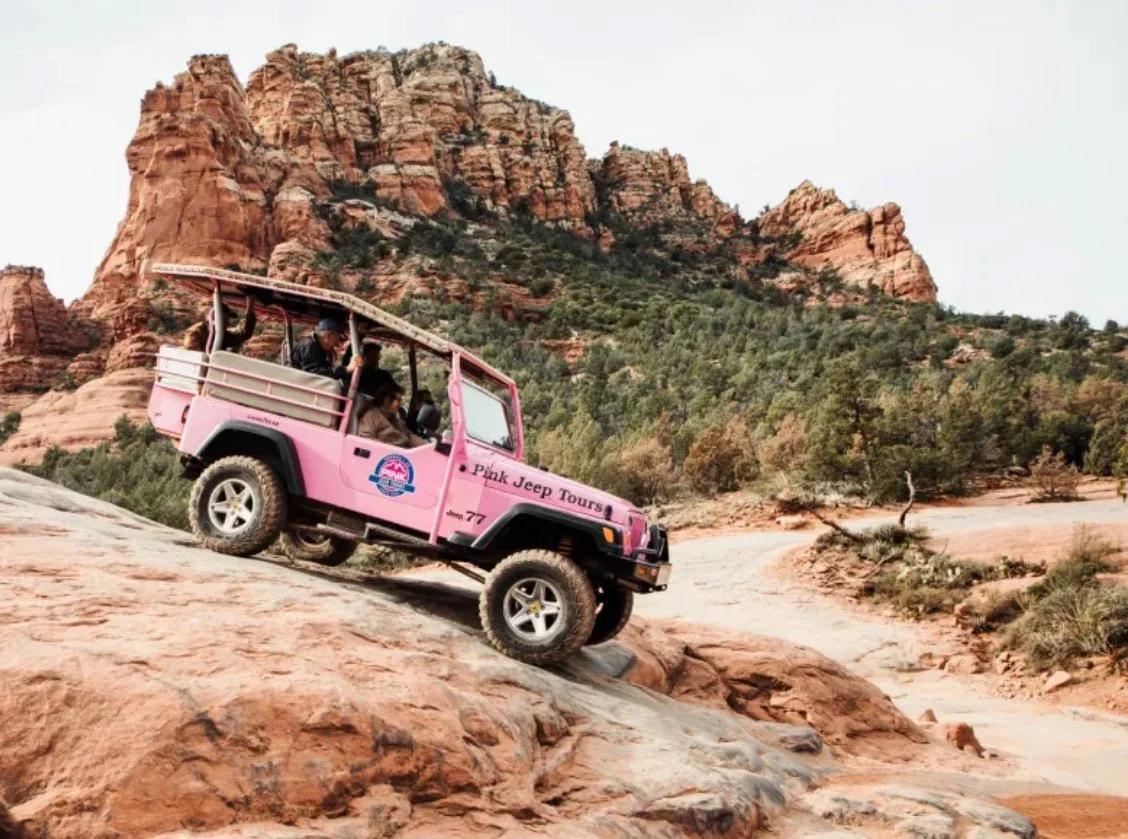 Off-road jeep descending a steep red rock slope during Sedona Pink Jeep Tours, showcasing the rugged landscape