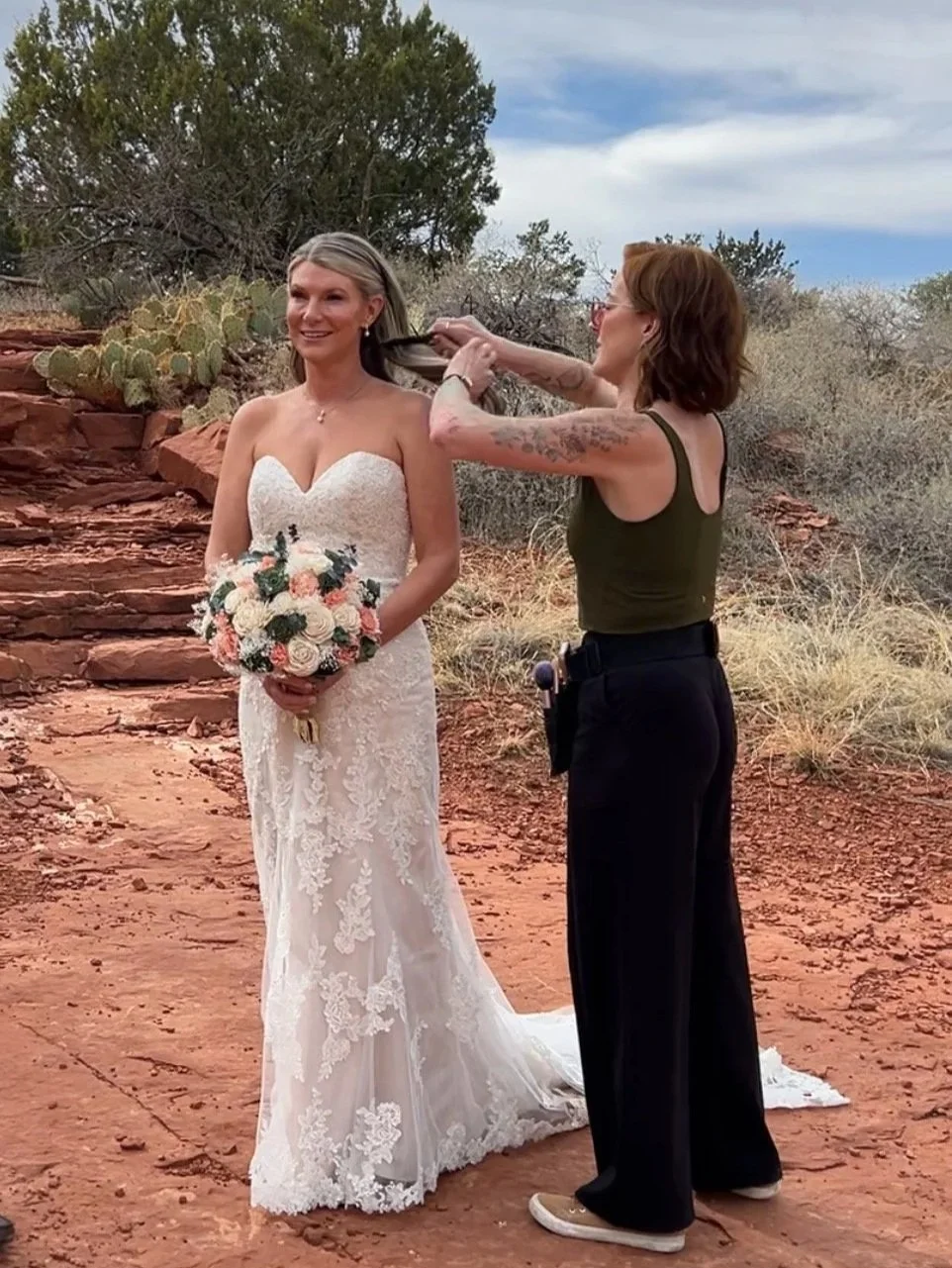 Sedona hair and makeup artist giving the bride final touchups before family photos with the red rocks in the background