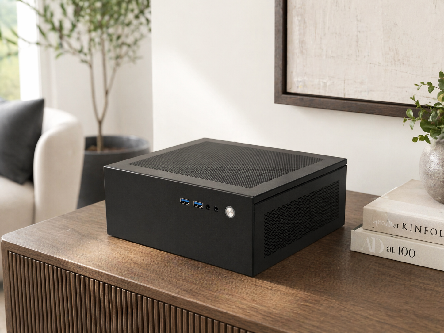 Black desktop computer case with USB ports, a power button, and ventilation grills, placed on a wooden table next to a stack of books and a potted plant.