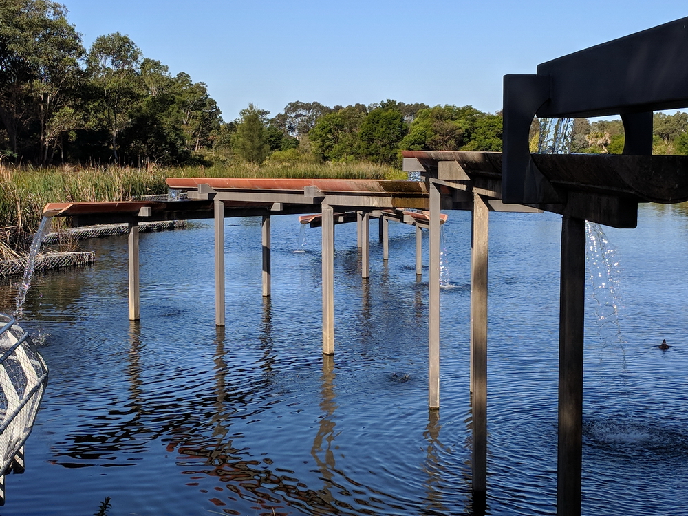Cascading water flows out of half-pipes over lake