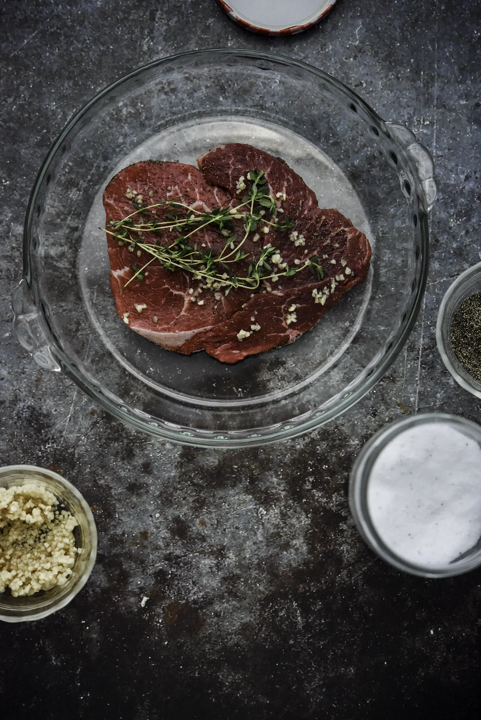 Sirloin steak with garlic and thyme. Food photography, food styling, and prop styling by Megan Crist.