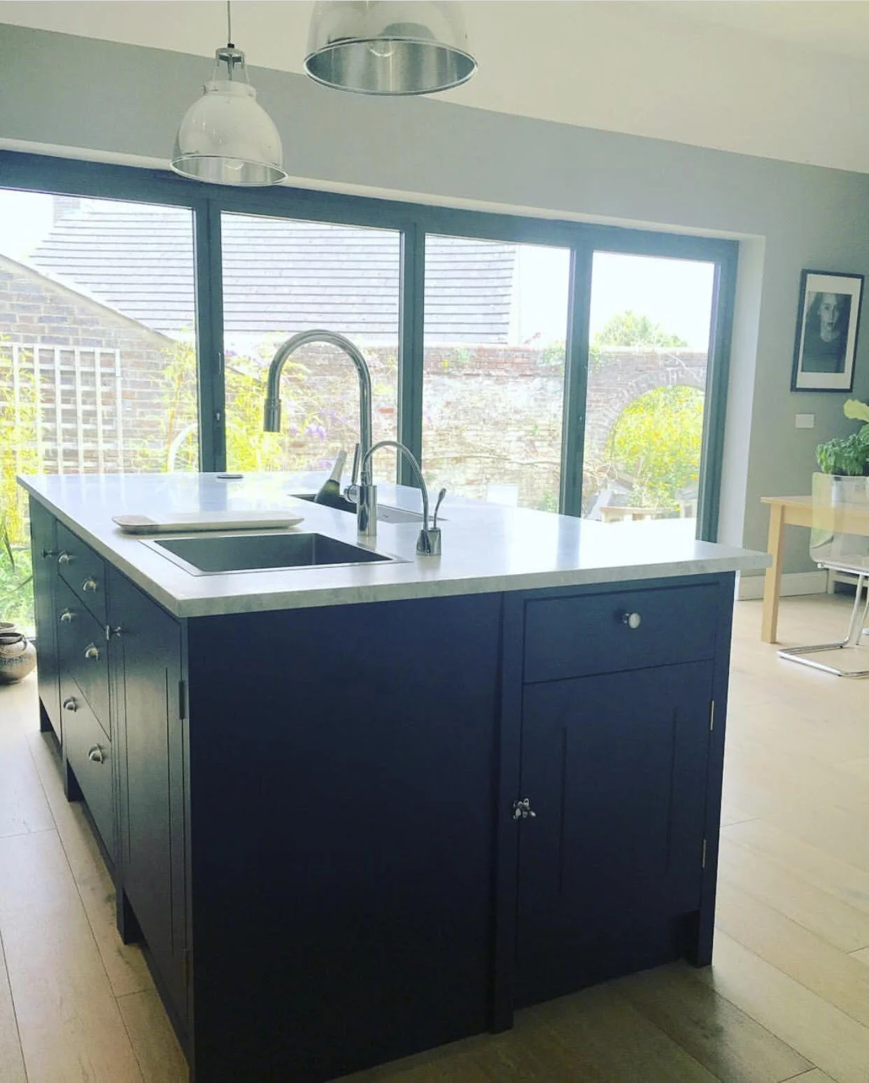 First photo of the island for Instagram...... There is an abundance of natural light thanks to the bifold doors and as it’s quite a large space with vaulted ceilings it can carry off a dark colour. The dark units don’t overwhelm the space but contrast beautifully with the brick wall and lime washed oak floor and I love the view of the garden courtyard through the full width doors.