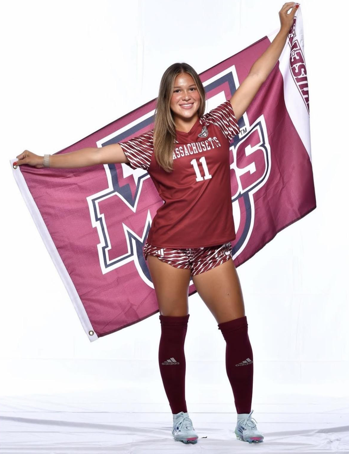 A female soccer player in a blue and black uniform controlling a soccer ball during a game on a green field.