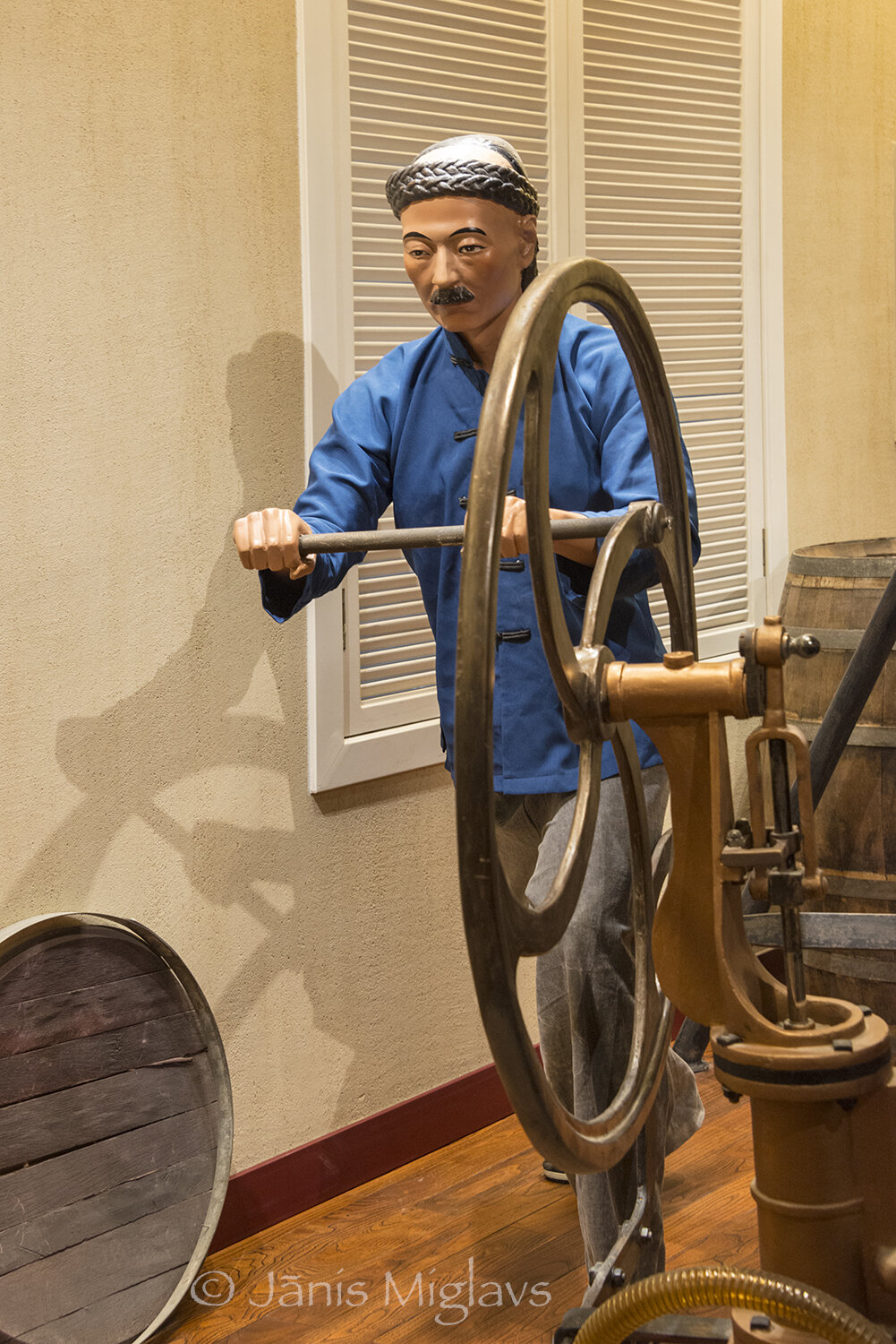 Model of Chinese worker working hand-powered grape wine press at winery visitor center.