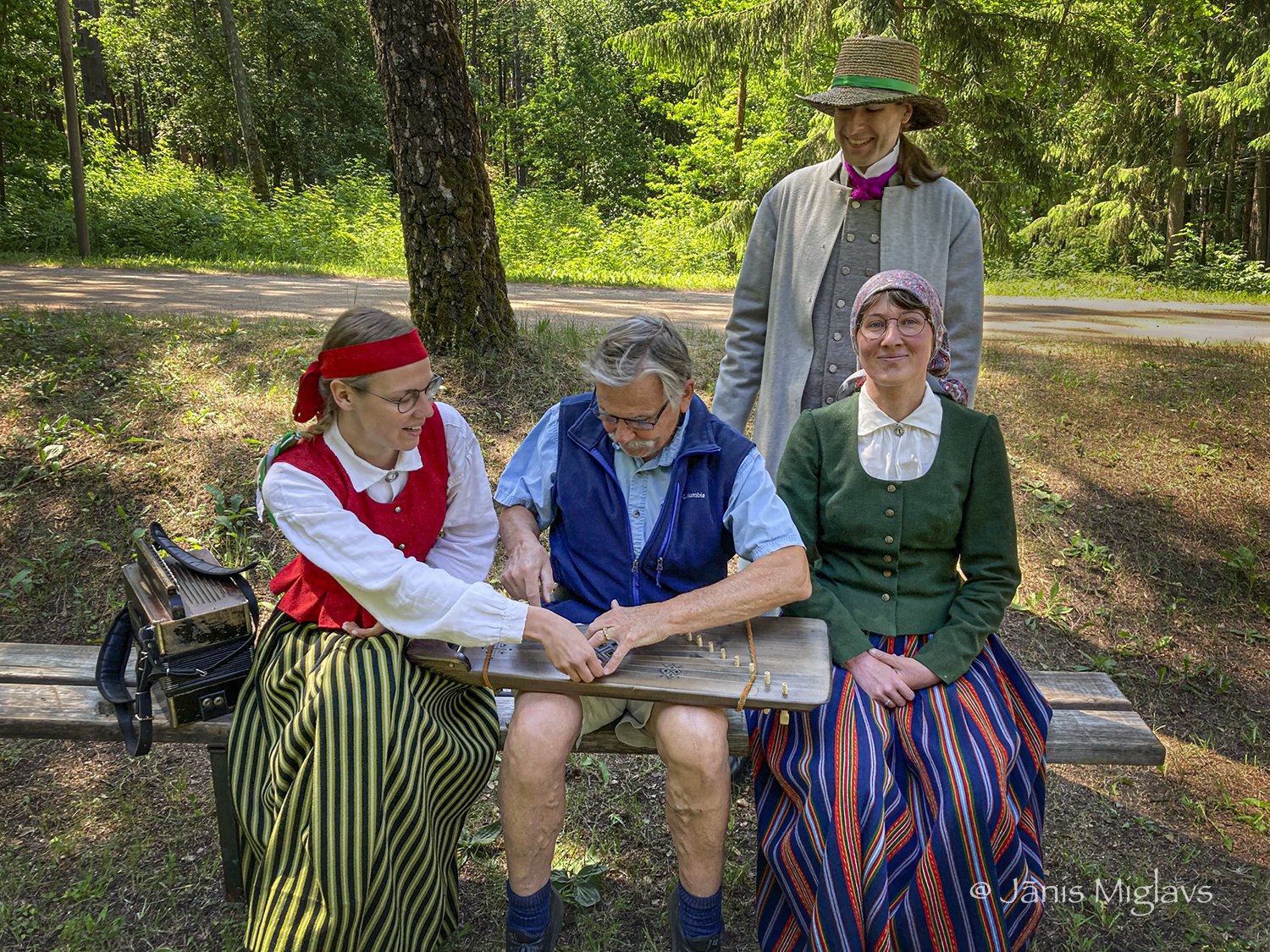 Musicians trying to teach Jānis to play the Latvian kokle 