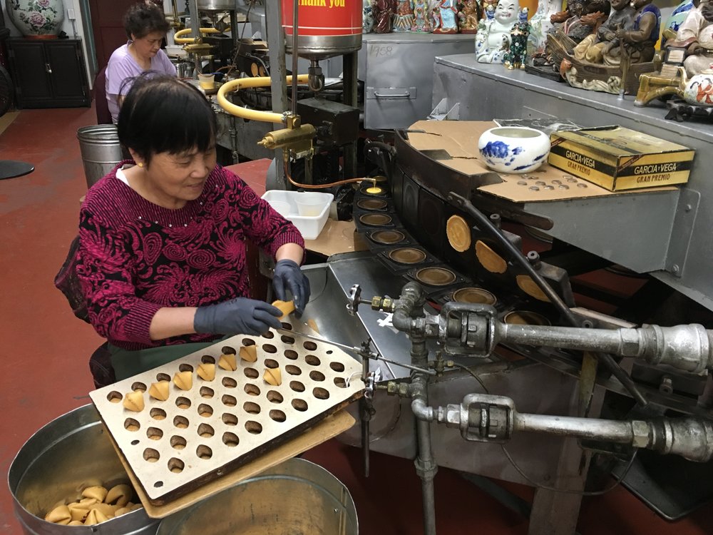 A worker making fortune cookies at the Golden Gate Fortune Cookie Factory
