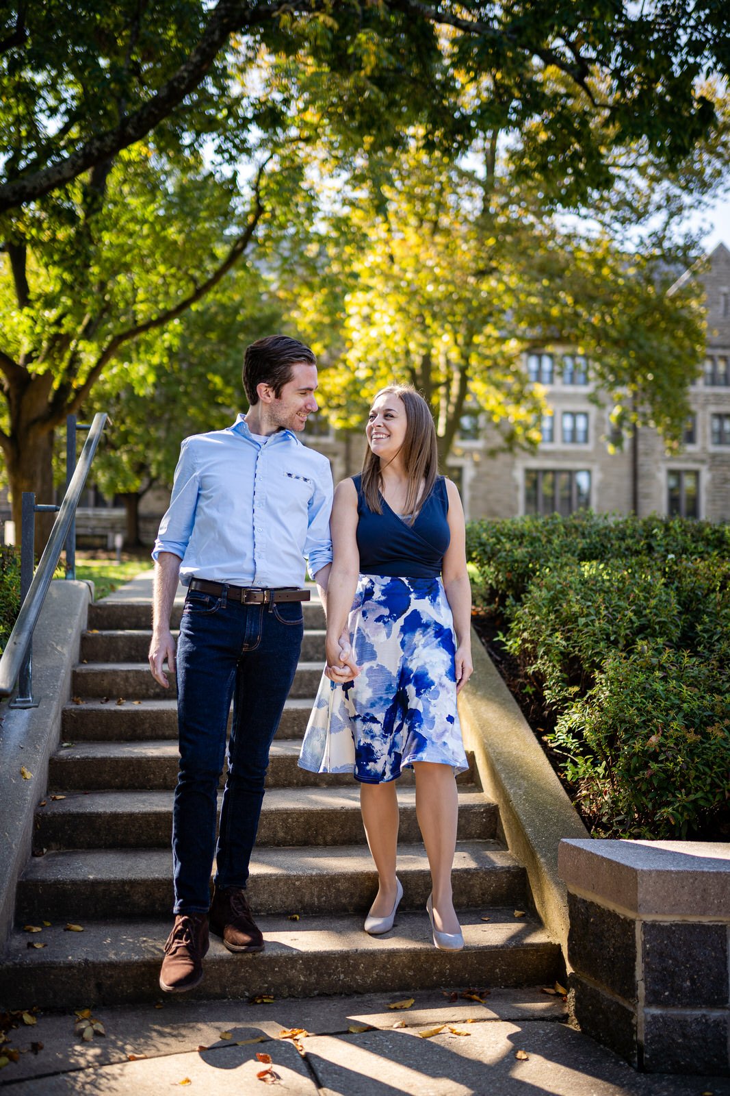 An engaged couple in blue walk steps in Villanova PA