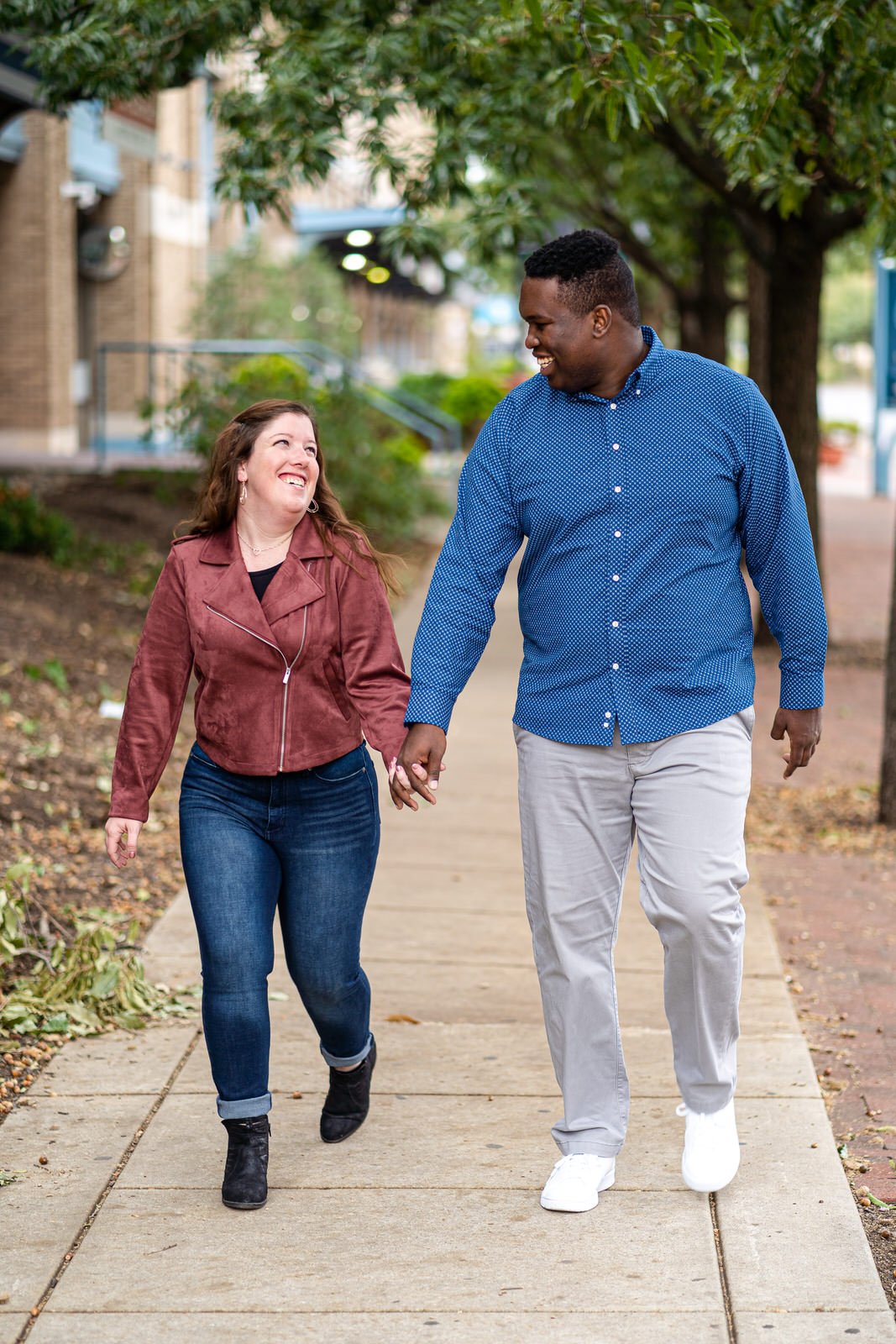 An engaged couple holding hands along the waterfront in Philadelphia PA