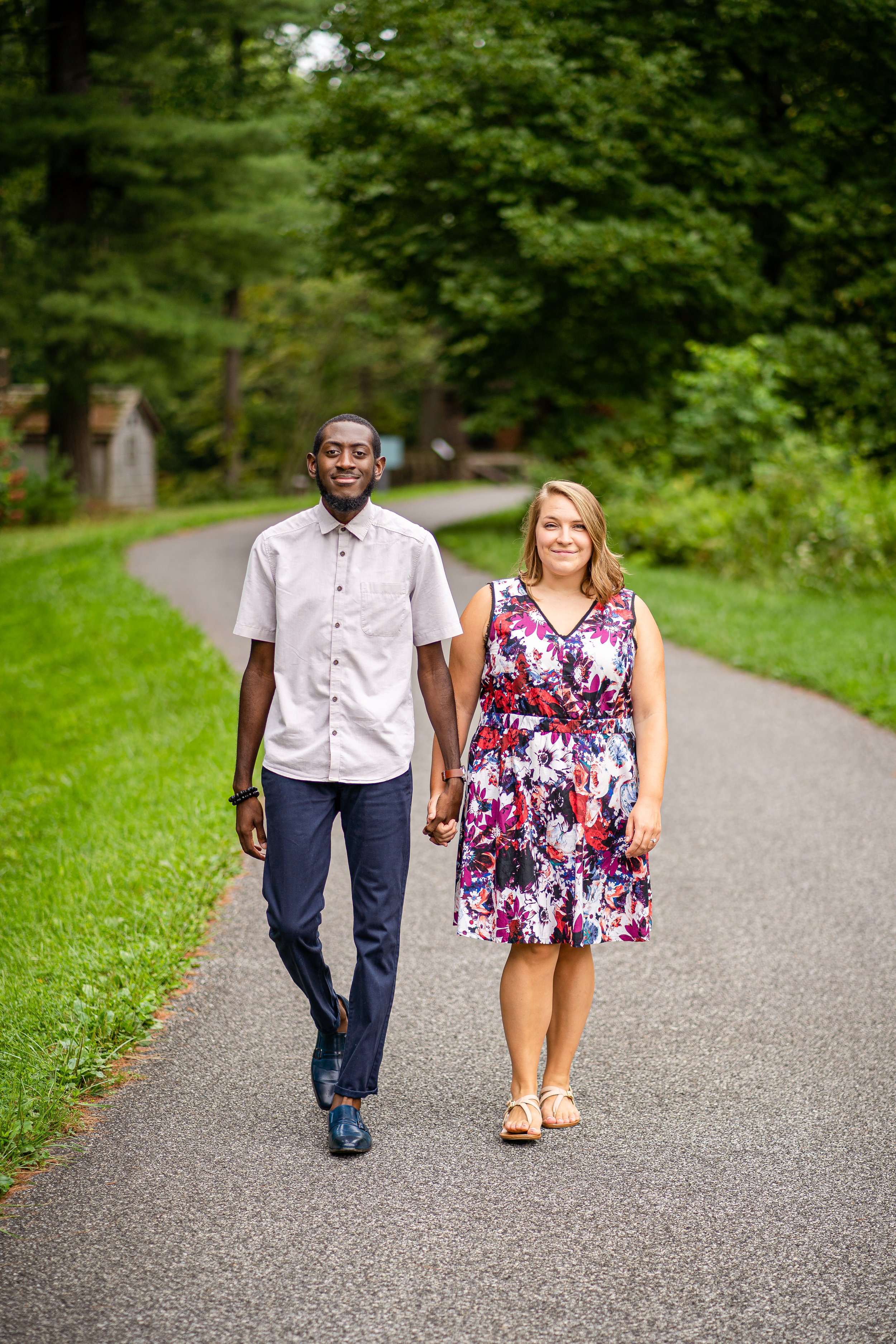 An engaged couple calmly walks along a path at Tyler Arboretum in Media PA