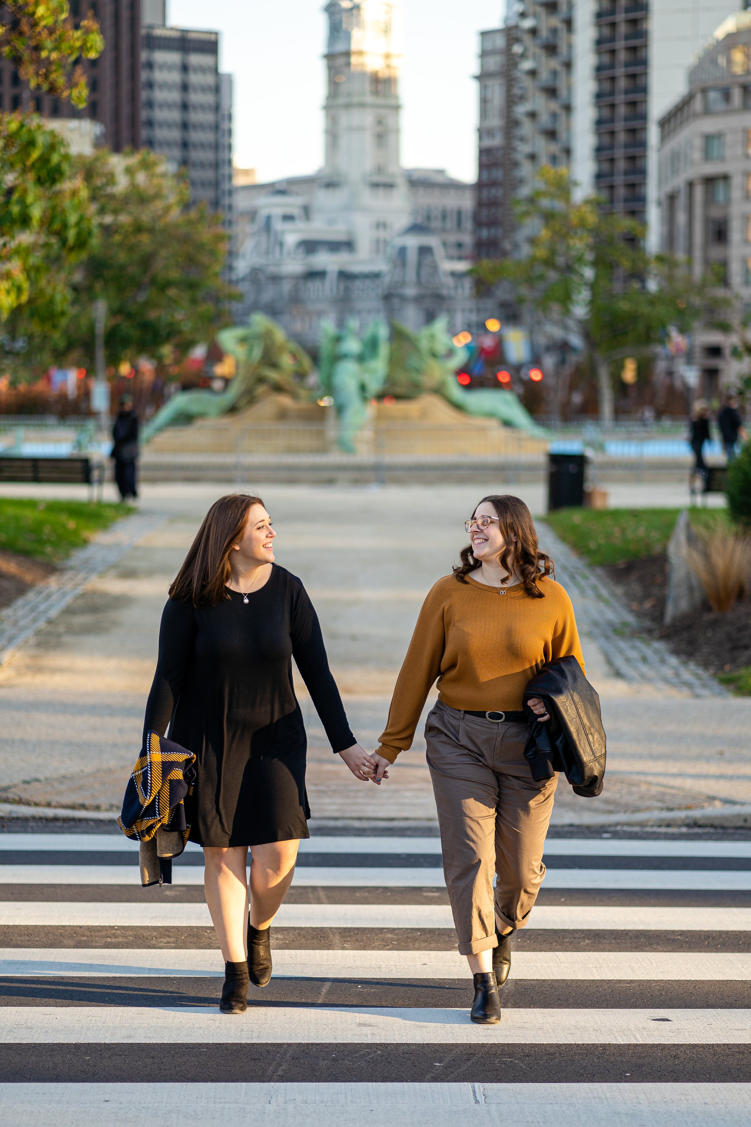 Two engaged women hold hands and smile in historic Philadelphia PA
