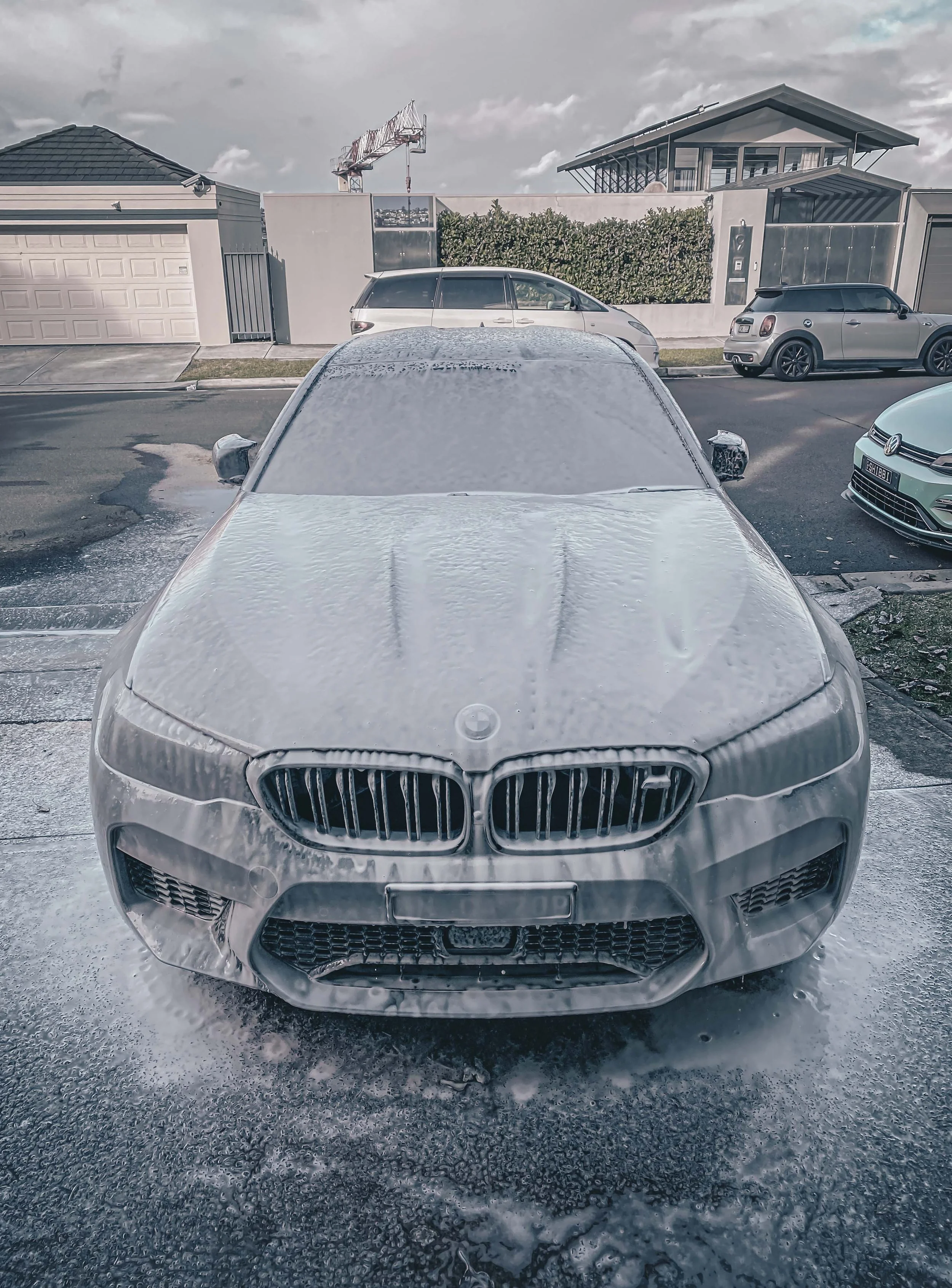 Shibbi Car Detail mobile car detailing applying pH neutral snow foam pre-wash to a BMW M5 in a driveway at Point Piper, Sydney, allowing the foam to dwell and lift dirt before pressure rinsing.