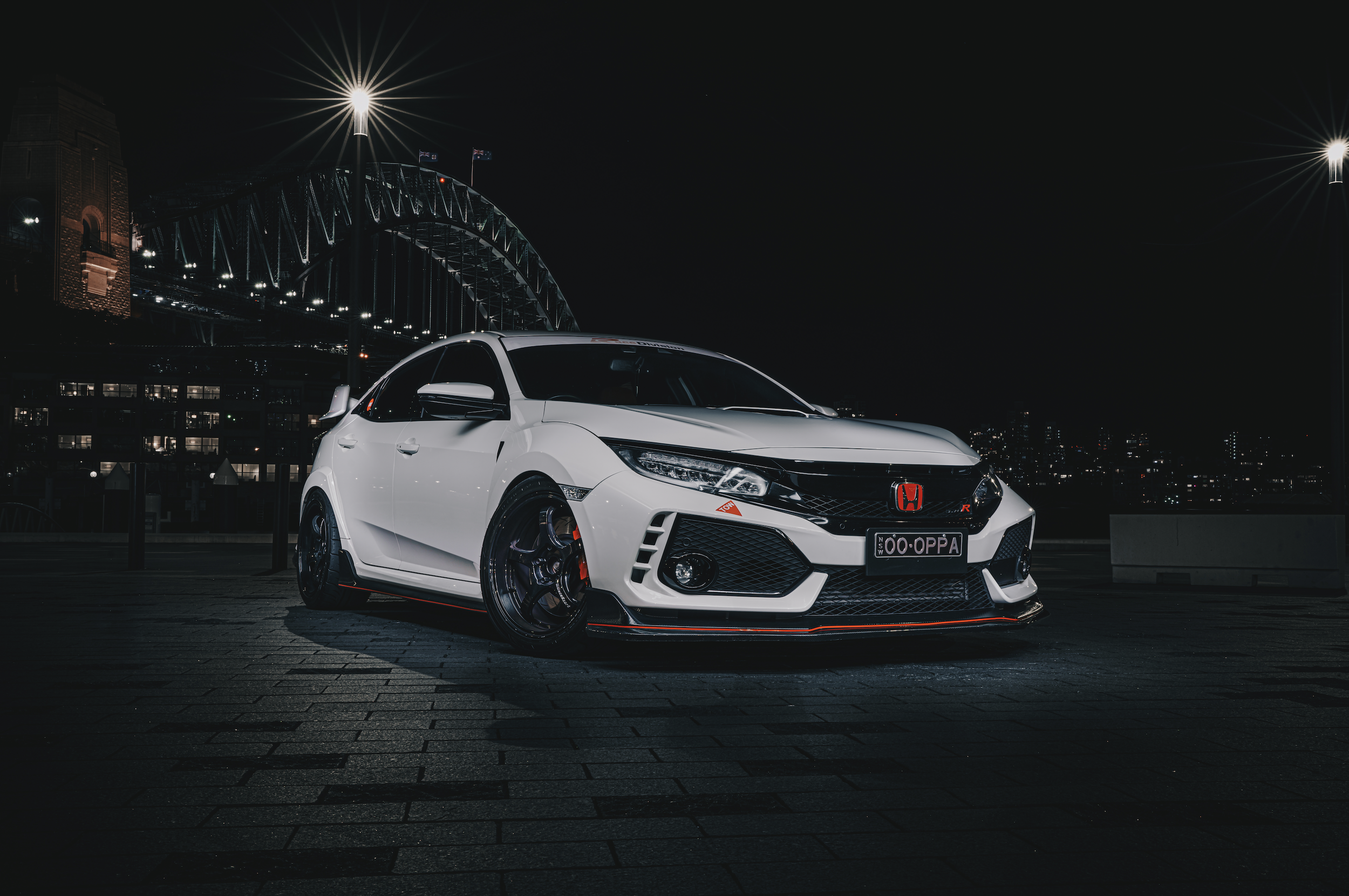 Shibbi Car Detail night photography of a Honda Civic Type R FK8 parked at Circular Quay with the Sydney Opera House and Harbour Bridge lights illuminating the background, showcasing the car's aggressive styling against the Sydney city skyline.