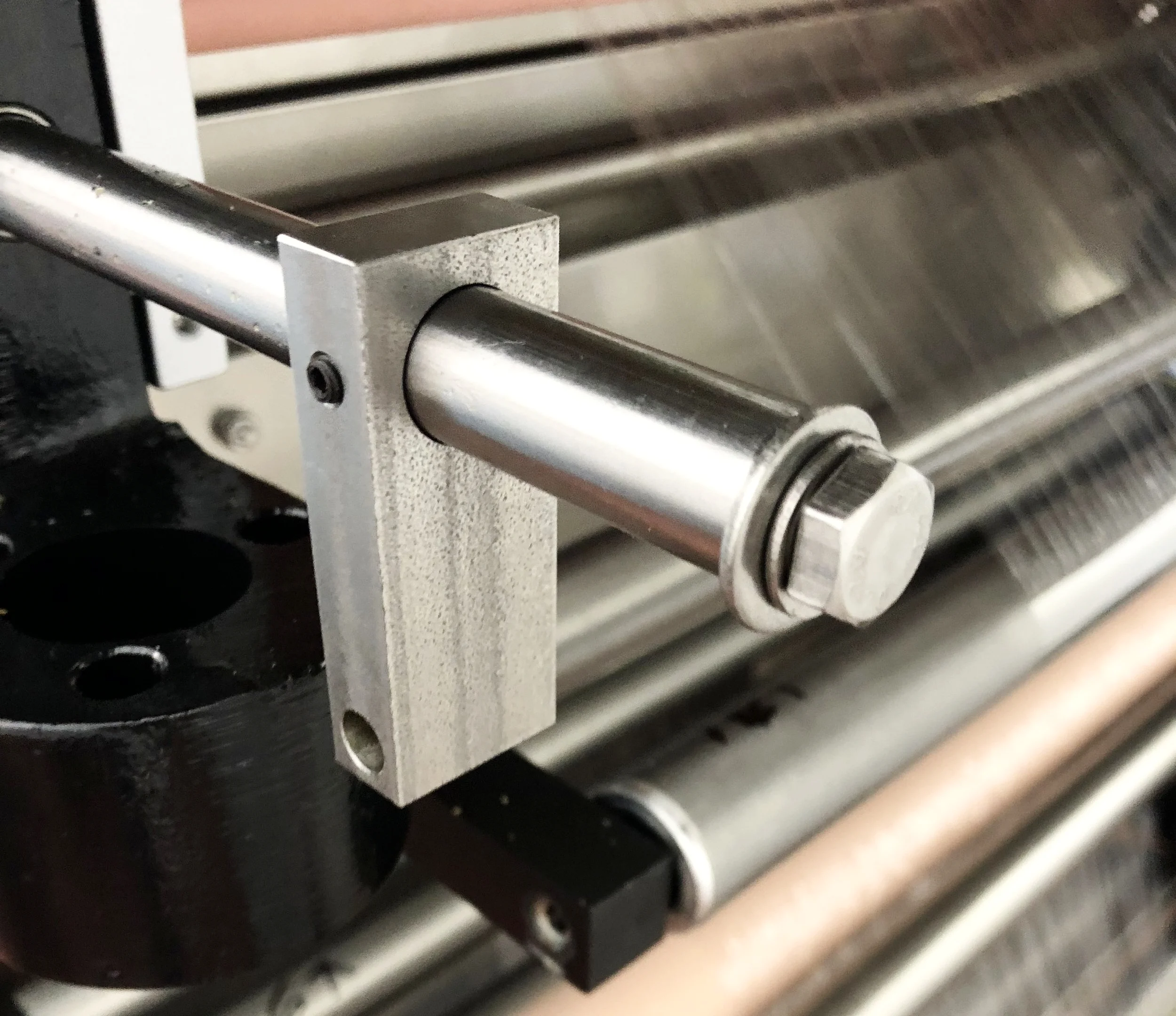  We wanted a simple, semi-permanent solution that could handle everyday use. The horizontal rod was already part of the machine, so I decided to integrate this block onto that rod using a small set screw. This allowed for easy installation and remova