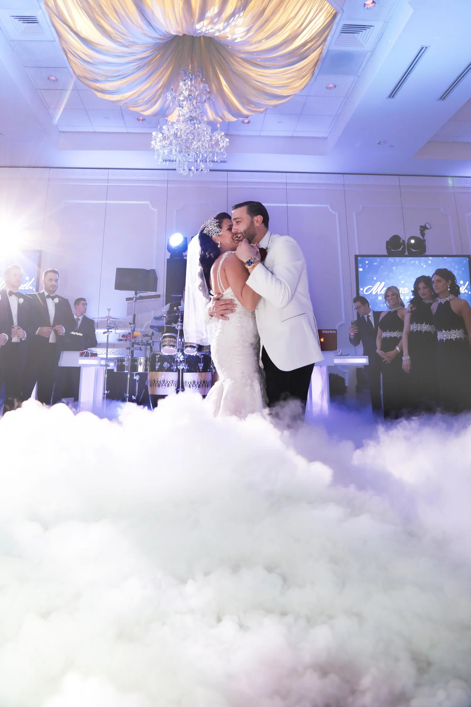 An E2 couple dancing on clouds surrounded by their wedding guests