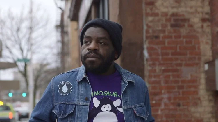 Hanif Abdurraqib walks down the street, gazing stoically into the distance.