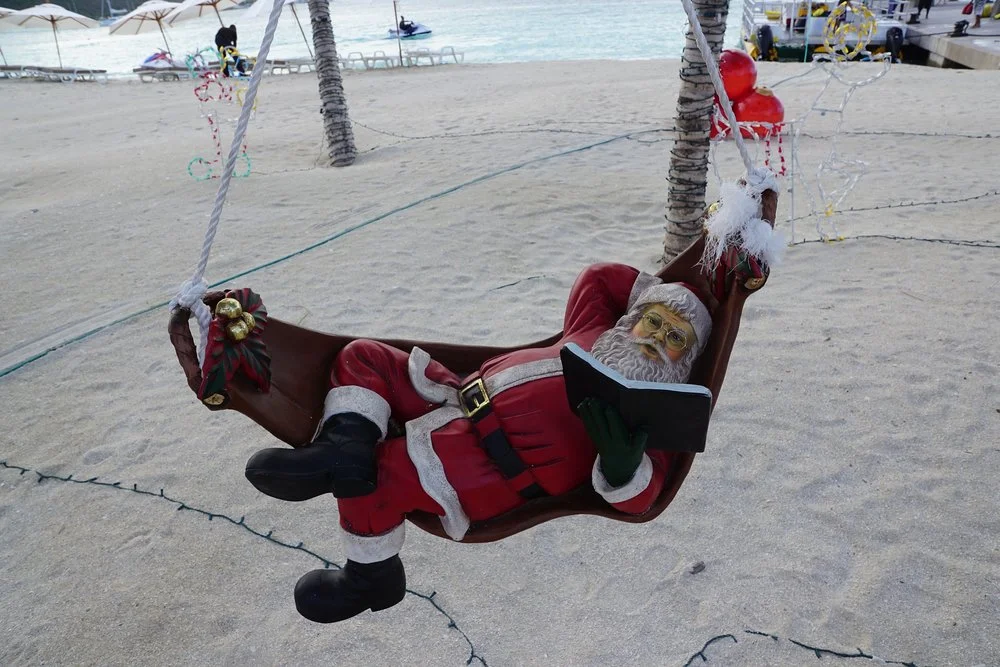 Santa has this “light reading” thing down, but his beach attire still needs some work.