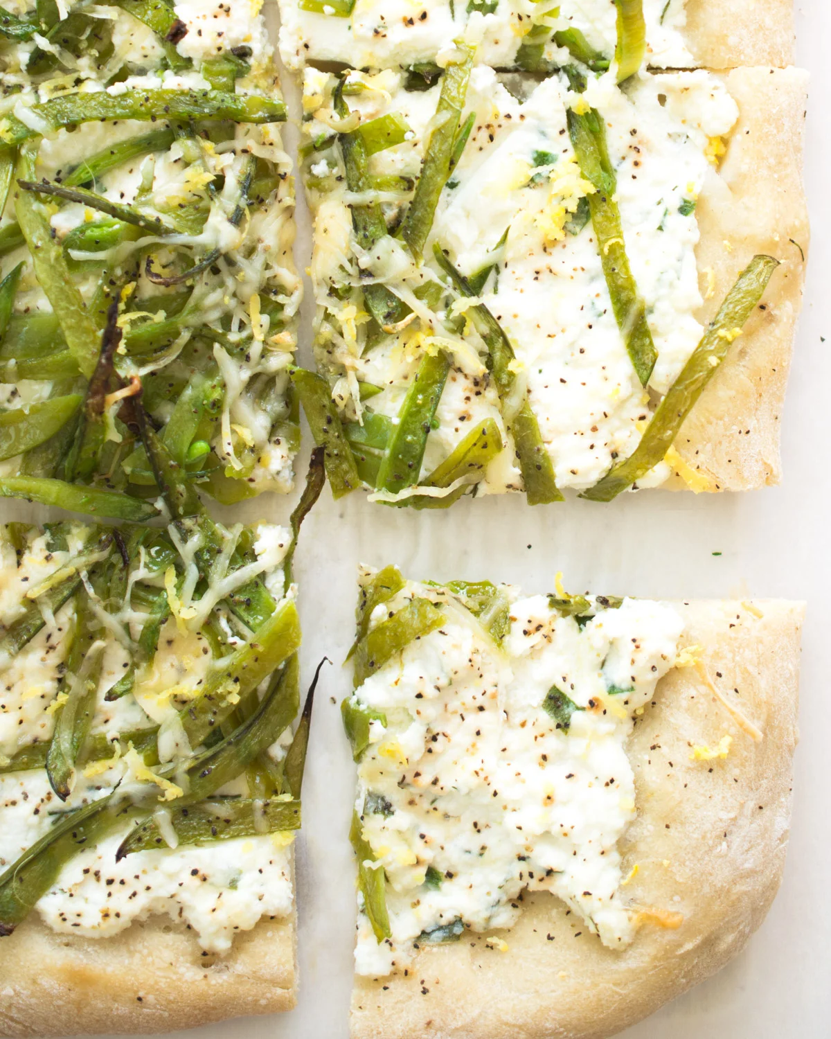 Pizza topped with herbed ricotta and sliced fresh snow peas.