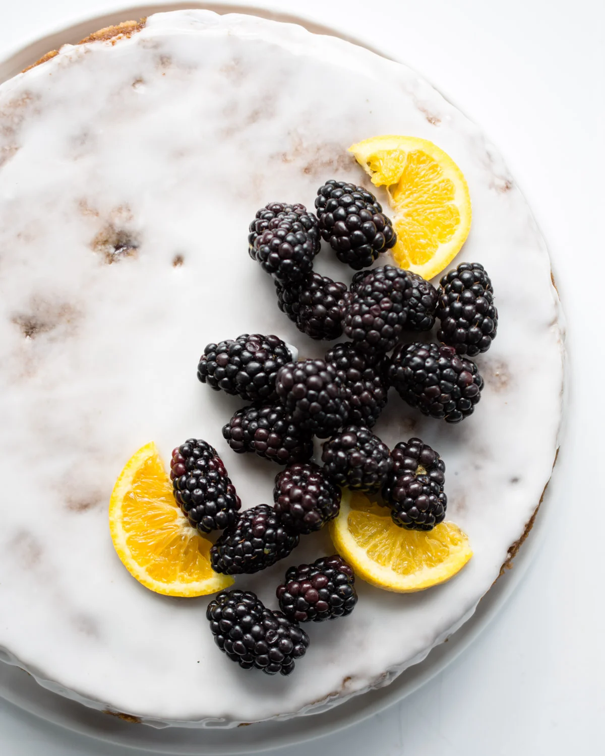Orange Blackberry Olive oil Cake garnished with fresh blackberries and orange slices.