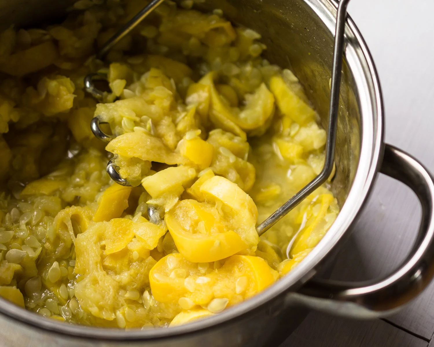 Mashing cooked yellow squash.