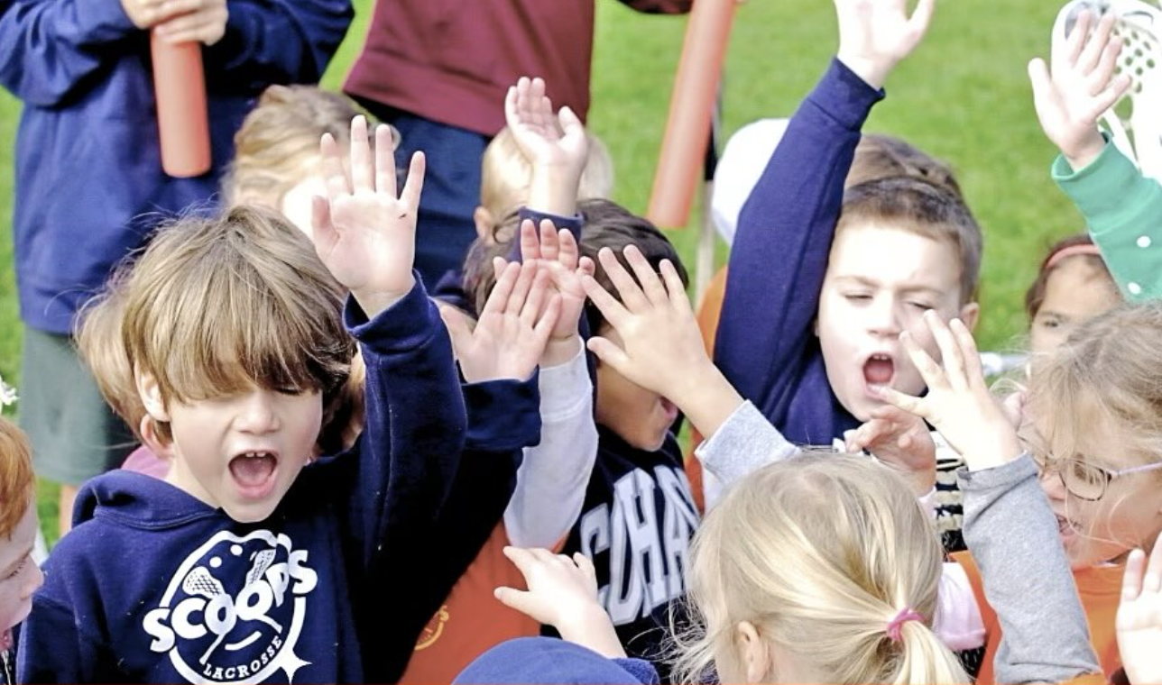 Group of children raising their hands together outdoors