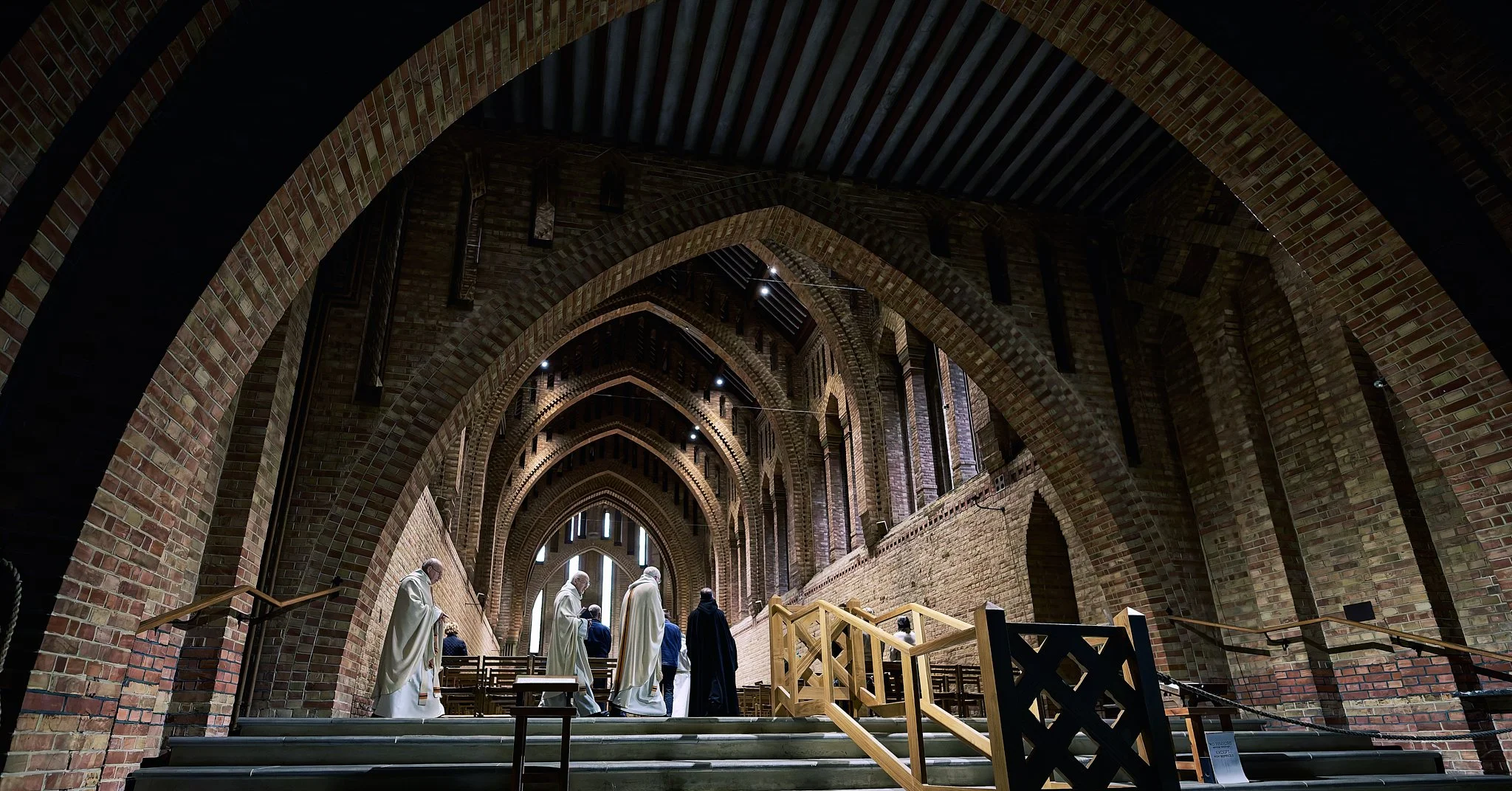 This documentary fieldwork photograph shows monks entering Quarr Abbey to celebrate Mass. It shows the incredible, proportioned arches that lead them to the sanctuary.