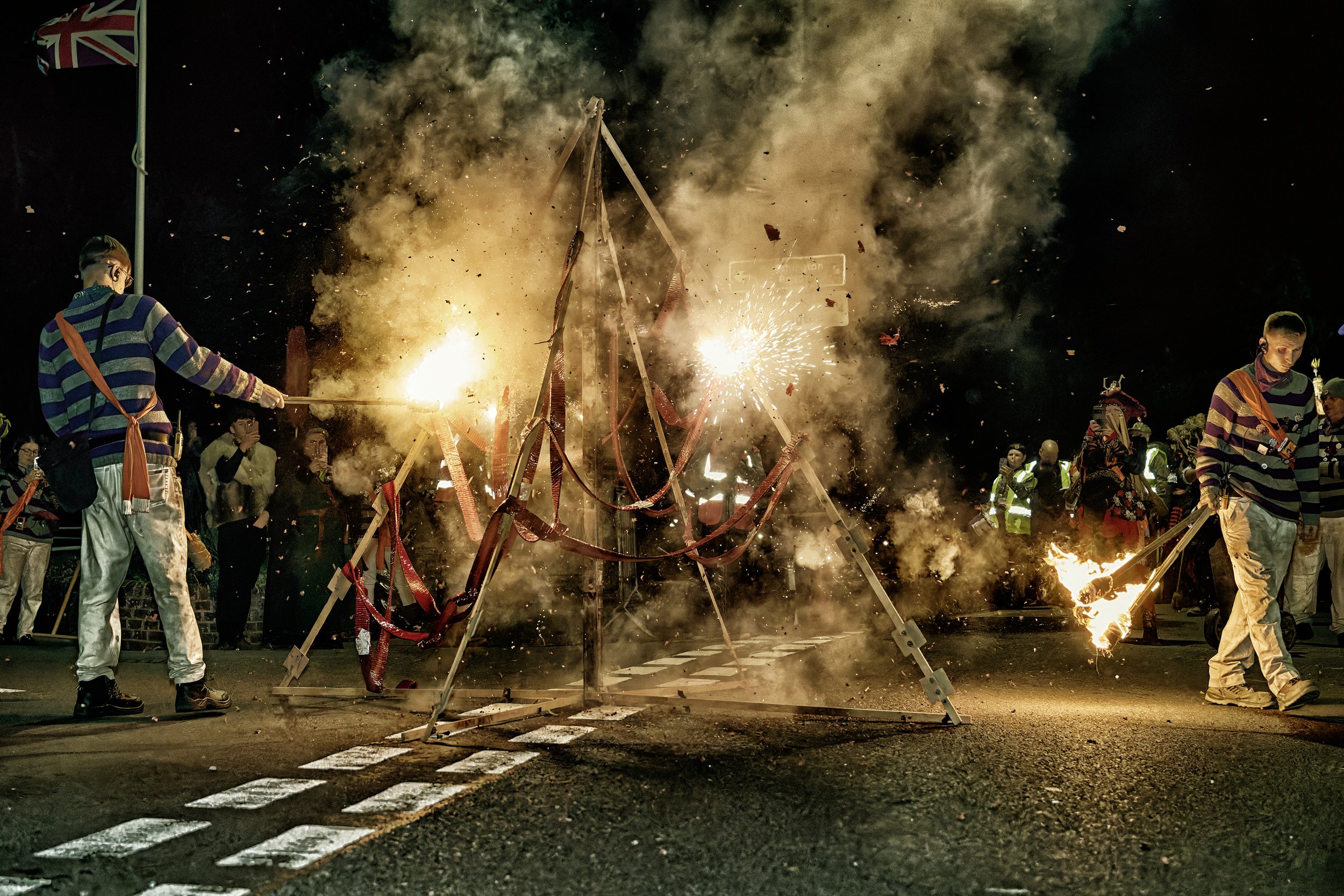 Documentary fieldwork photograph of a Sussex Bonfire Society parade in Seaford, showing spectacular ground fireworks