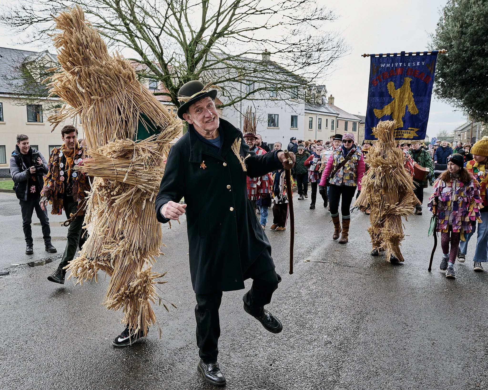 Documentary fieldwork photograph of the Straw Bear and handler in Whittlesey, showing street dancing