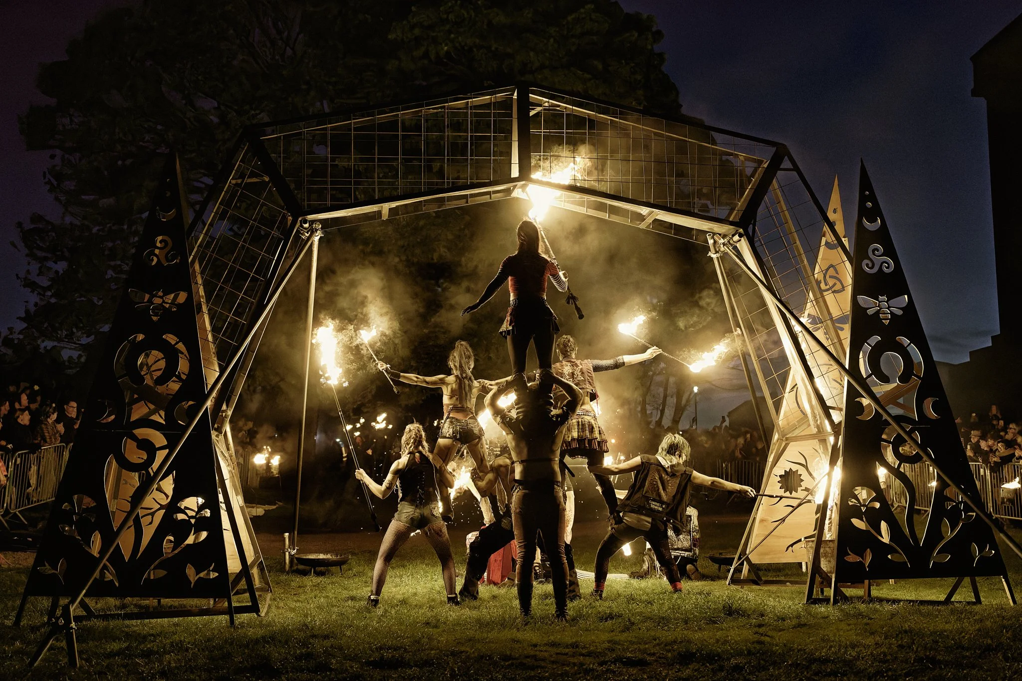 This documentary fieldwork photograph is of team ‘Firearchy’ lighting the purification Arch through which the May Queen will lead the procession.